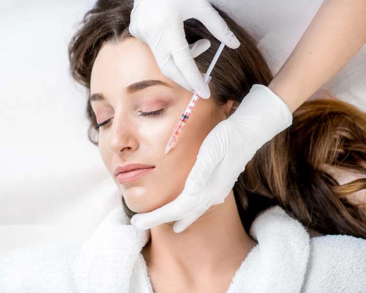 Aplicação de botox em rosto de mulher deitada em maca