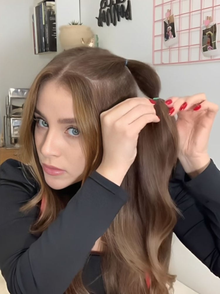 Menina prendendo elástico ao longo de uma mecha de seu cabelo.