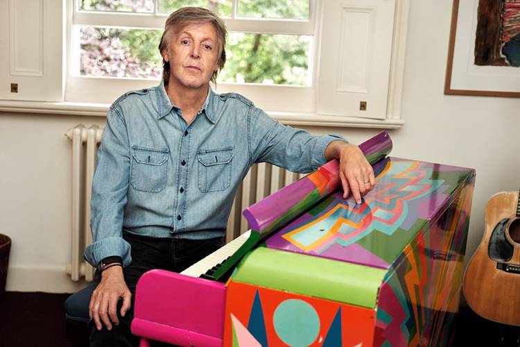 Cantor do Beatles sentado em mesa de piano colorida