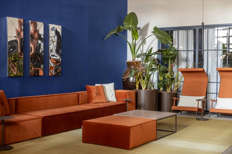 sala com móveis marrons, parede azul e plantas.
