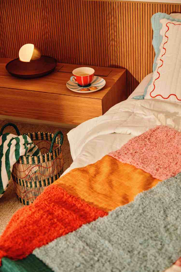 cama com almofadas e manta estampadas de várias cores