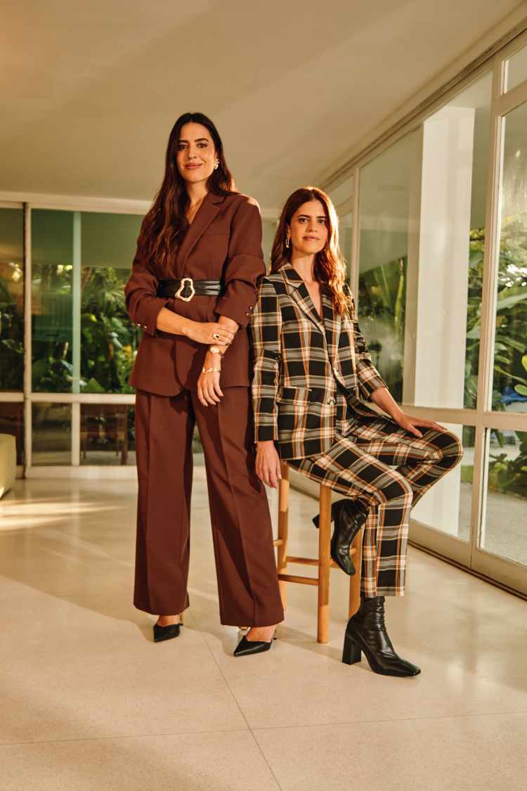 duas mulheres com conjunto de alfaiataria calça e blazer, a esquerda marrom e direita xadrez escuro