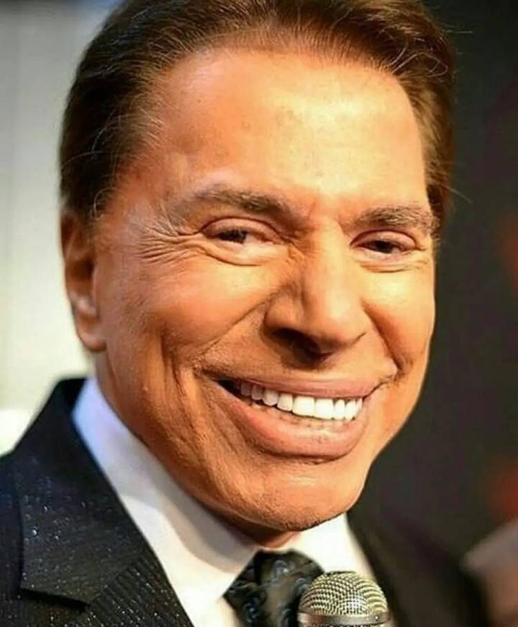 Rosto de Silvio Santos, ele sorridente usando terno e seu famoso microfone.