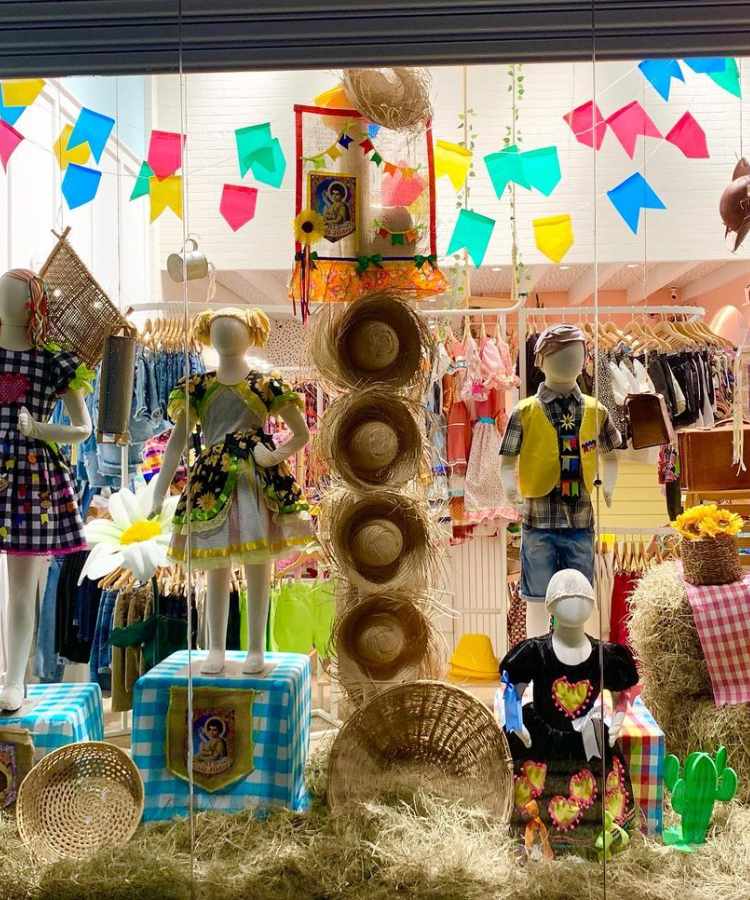 Loja decorada com tema são joão, chapéus de palha, bandeirinhas, feno, tecido xadrez, etc