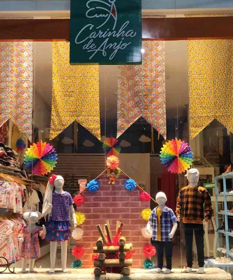 Loja decorada com tecidos estampados, fogueira falsa, e itens coloridos decorativos de festa junina