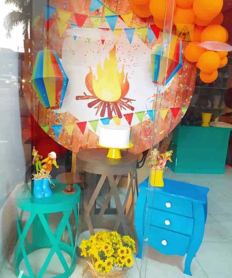 Loja com vitrine decorativa de festa junina, espantalhos, balões, etc