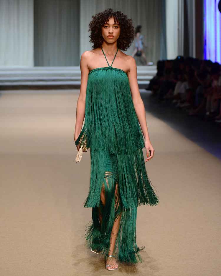 modelo em passarela com vestido de franjas verde
