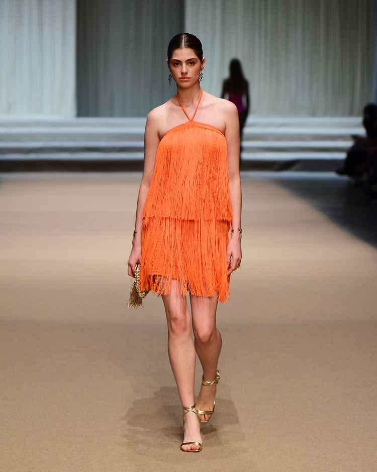 modelo em passarela com vestido de franja laranja