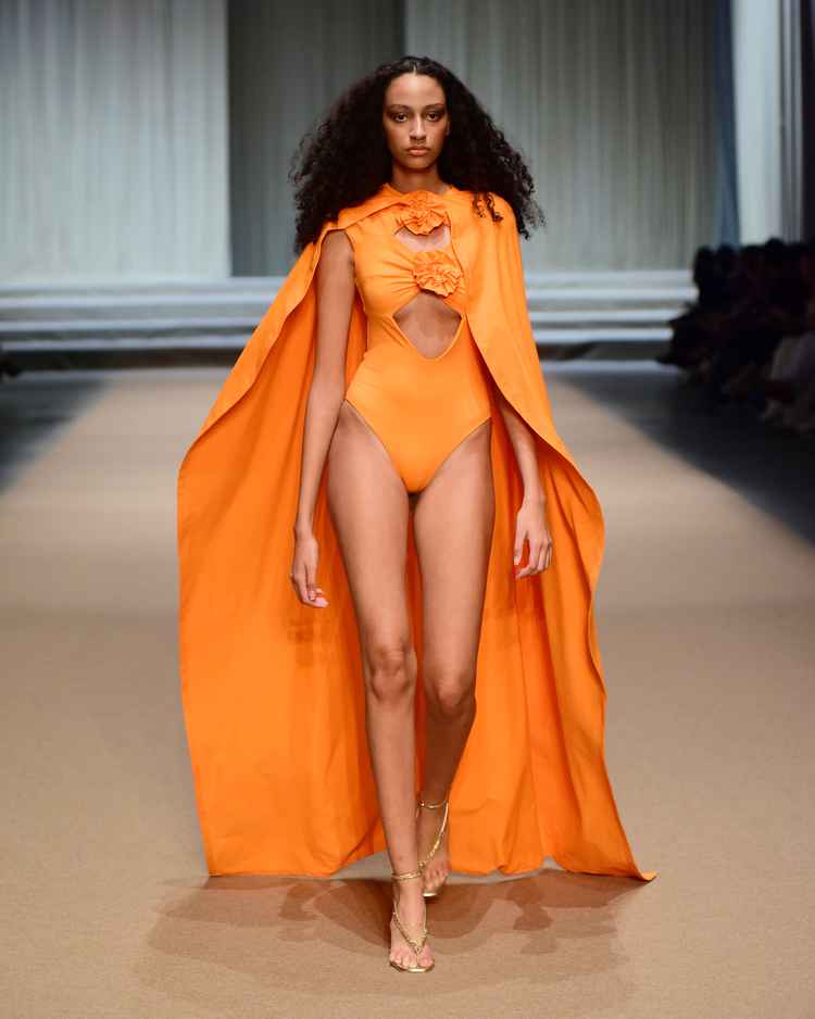 modelo em passarela com maio laranja e capa de mesma cor