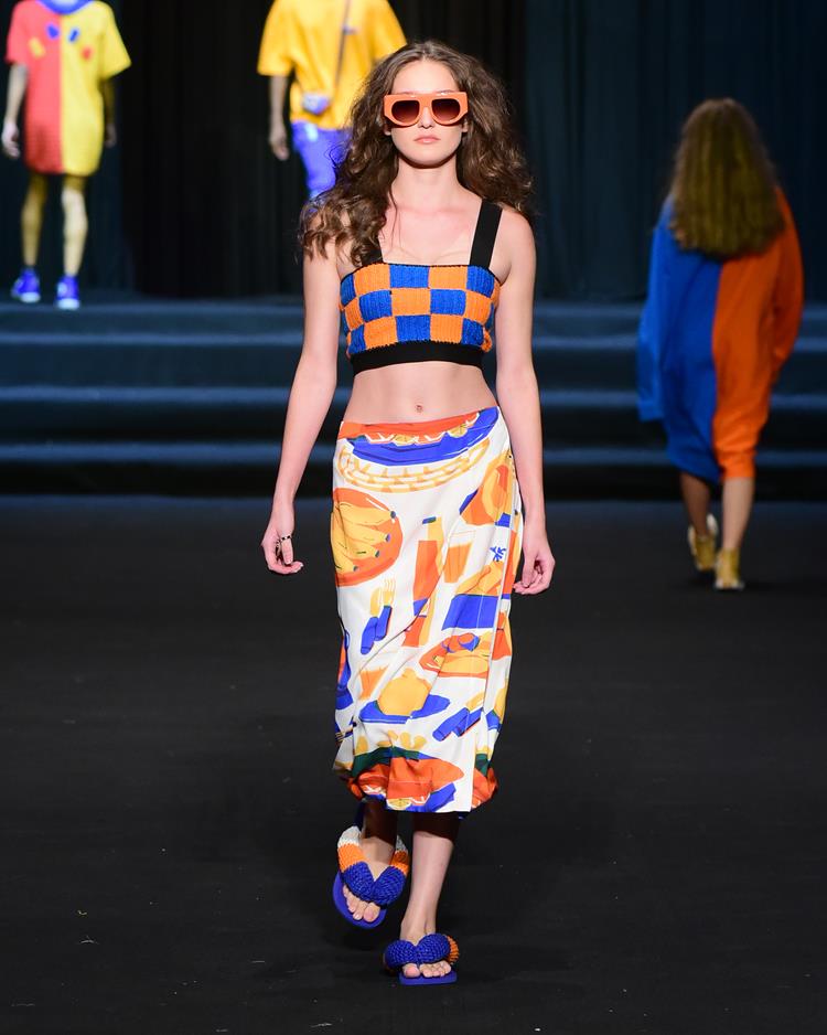 modelo na passarela com saia e top estampados nas cores azul e laranja