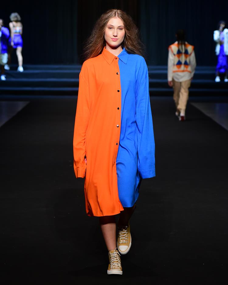 modelo na passarela com vestido longo metade azul e metade laranja