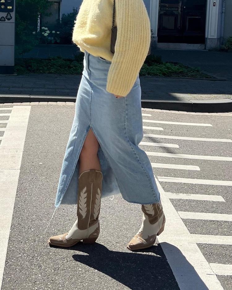 mulher com blusa amarela, saia longa jeans e bota western marrom e branca