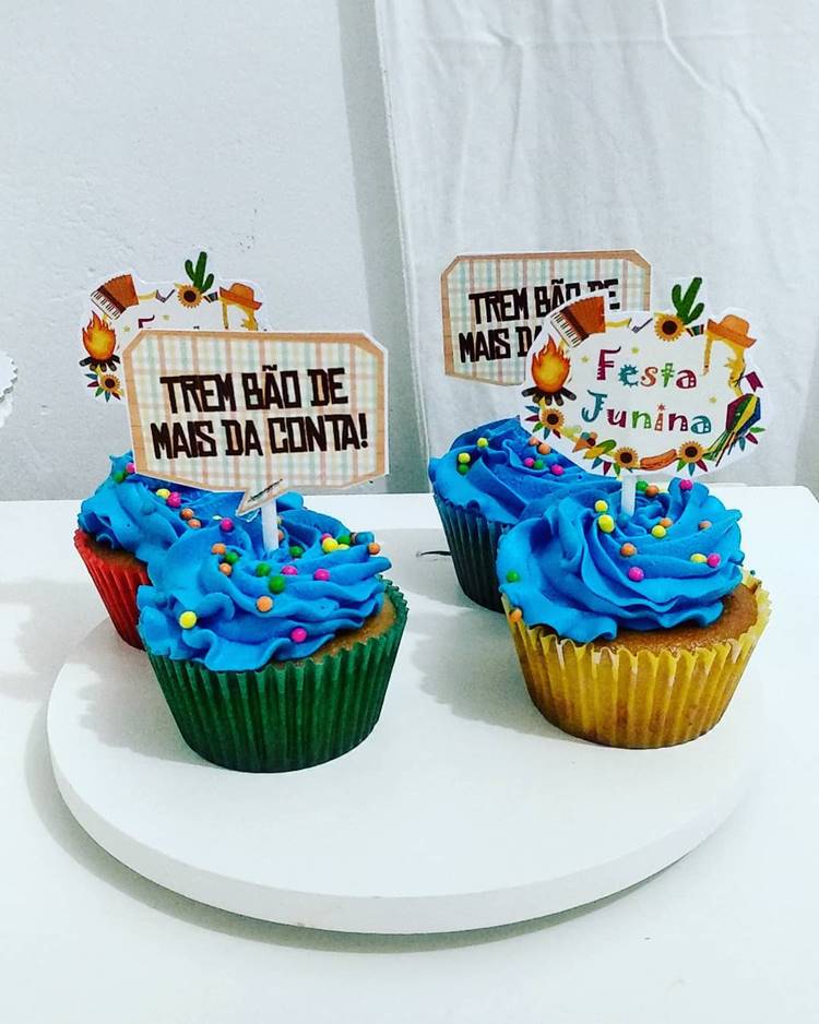 Cupcakes azuis de chantily com granulado colorido e toppers de frases típicas de São João
