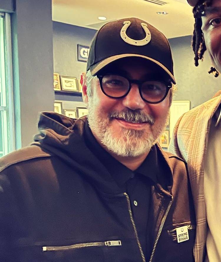 Ator Danny Nucci hoje, em 2023, do filme Titanic,. com cabelos e barba grisalhos, óculos, boné com símbolo de ferradura e jaqueta preta