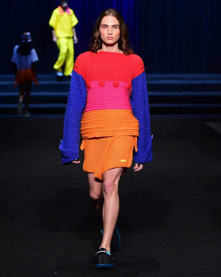 Modelo com casaco colorido e shorts em crochê em desfile no DFB Festival 2023