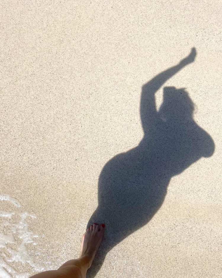 foto de sombra de mulher na areia da praia