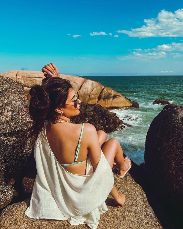 foto de mulher sentada em pedras na praia