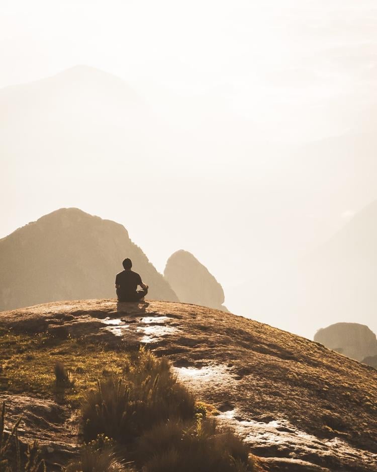 foto de homem sentado em paisagem de montanhas 
