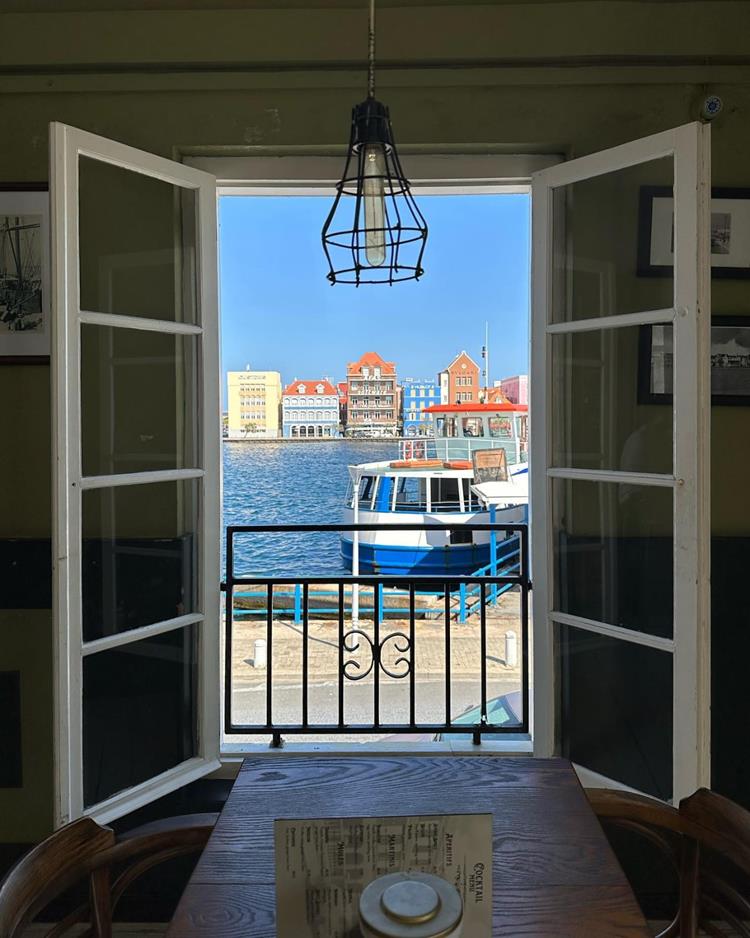 foto de janela com paisagem de mar e casas coloridas