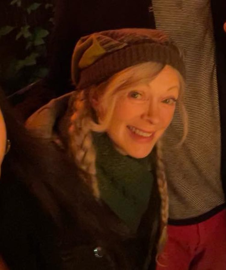 Atriz Frances Fisher hoje, em 2023, com touca, duas trancinhas e roupa de frio