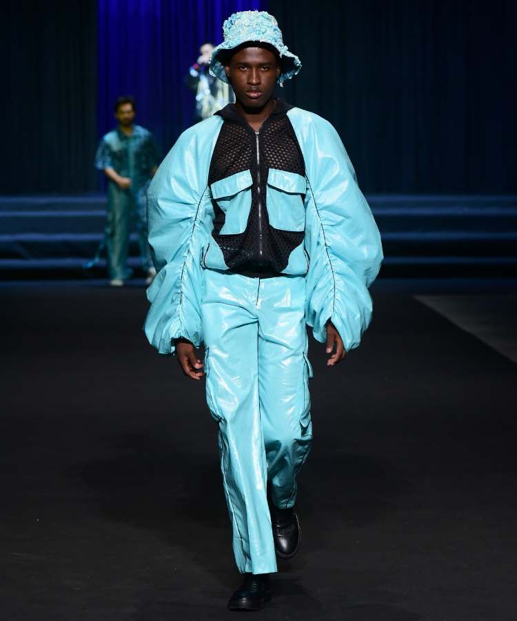 Modelo com jaqueta aconchoada + calça de couro - cores azul céu, no desfile de Kallil Nepomuceno no DFB Festival 2023