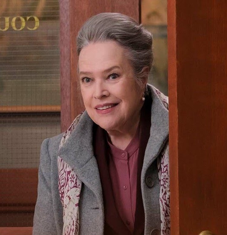 Atriz Kathy Bates, de Titanic, hoje em dia no filme Matlock (2023). Em porta de local, com casacos de frio.