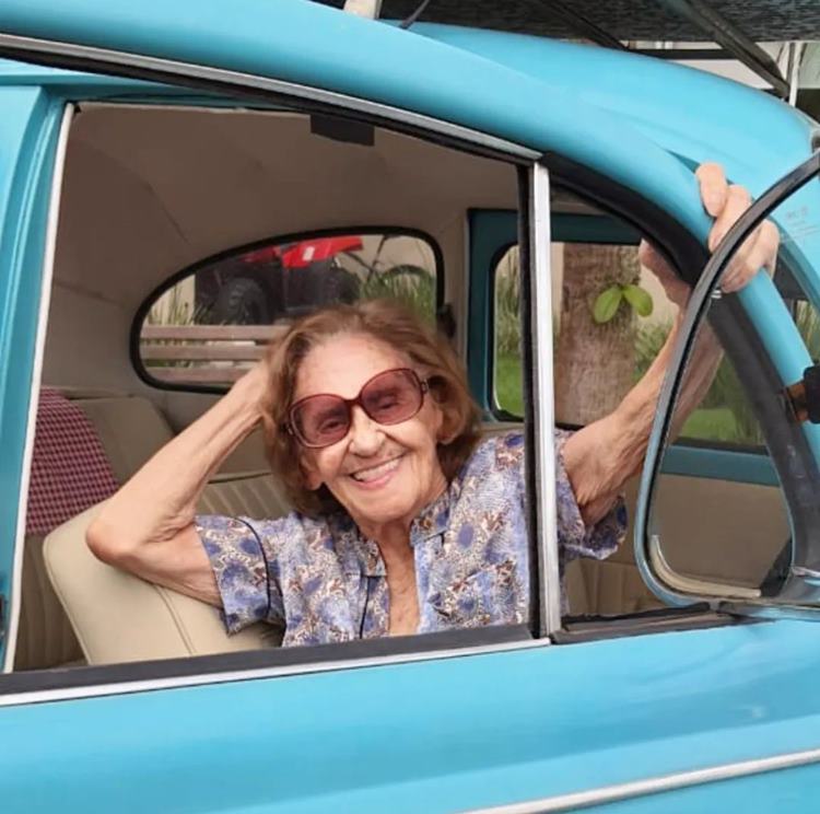 Atriz Laura Cardoso hoje, aos 95 anos, em foto sorridente dentro de fusca azul