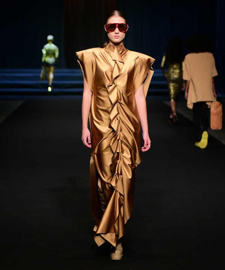 Modelo usando vestido de cetim dourado no desfile do DFB Festival 2023
