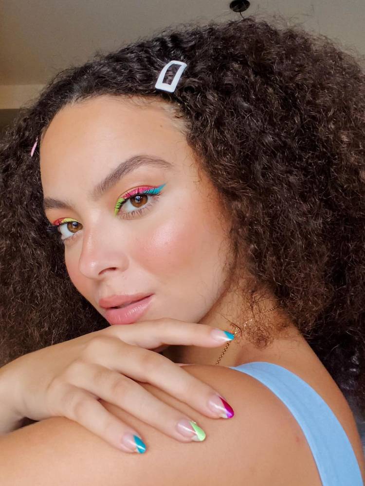 Julia Rodrigues com unhas coloridas, sombra colorida e presilha prateada no cabelo