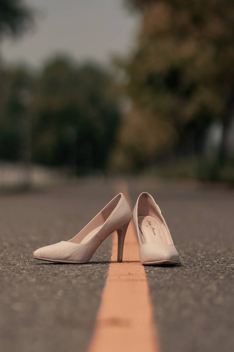 par de sapatos de salto alto brancos na estrada