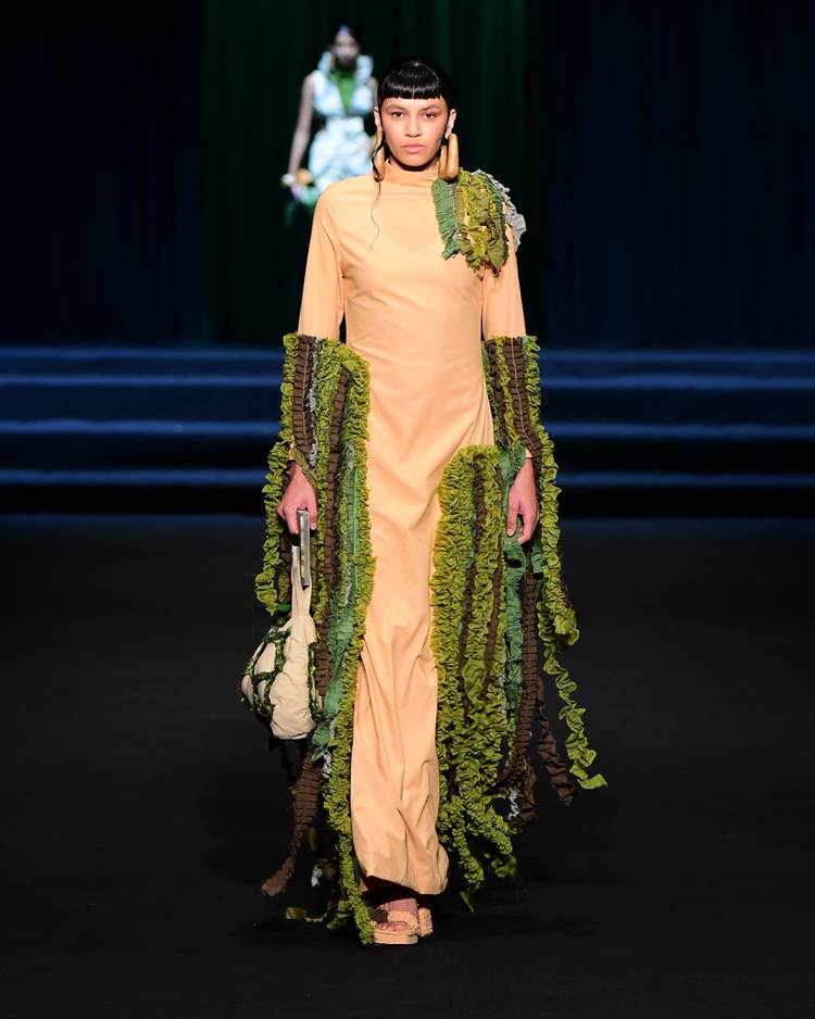Modelo com vestido bege com detalhes em verde e marrom no desfile da UNAMA no DFB Festival 2023