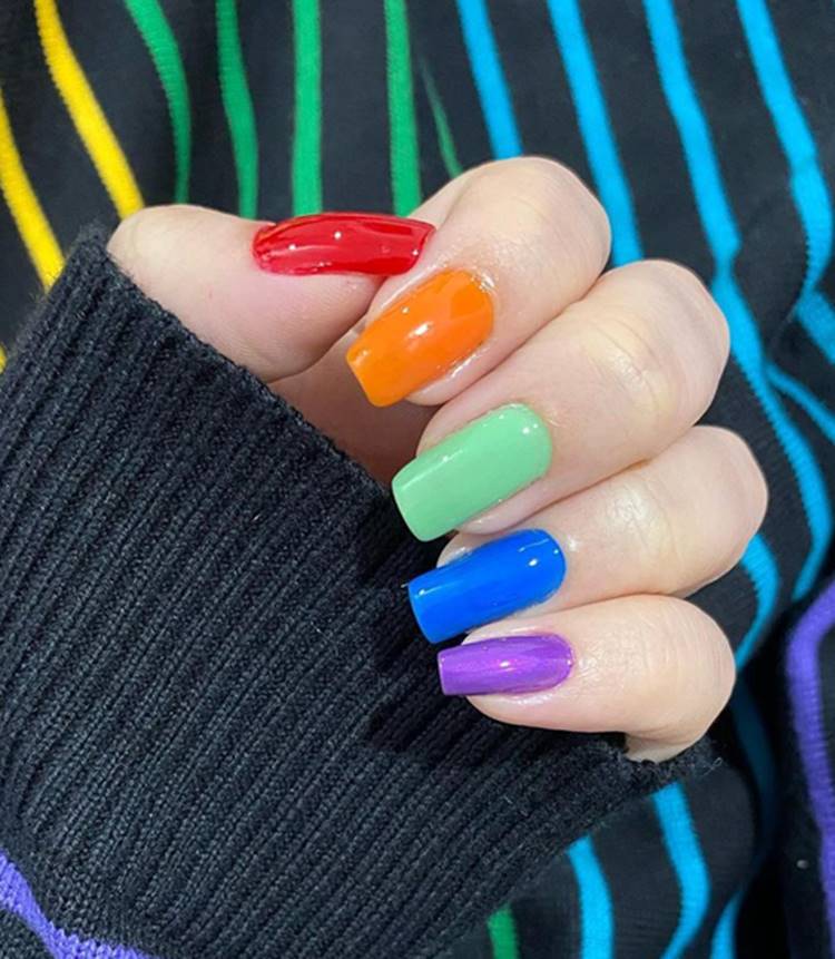 Mão com unhas arco-íris LGBTQIA+: Polegar: vermelho Indicador: laranja Médio: verde Anelar: azul Mínimo roxo