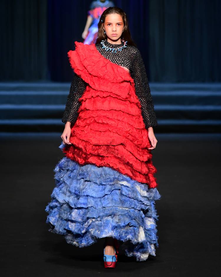 Modelo com vestido vermelho e azul com cropped em crochê no desfile da Uniateneu no DFB Festival 2023