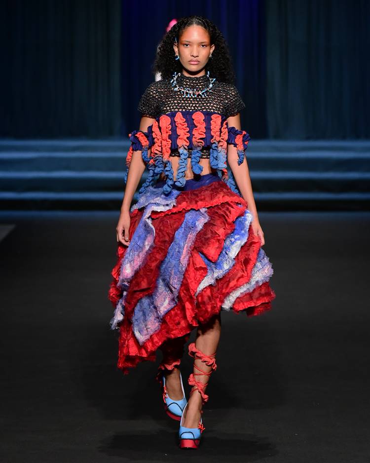 Modelo com saia vermelha e azul + cropped azul e vermelho de crochê + cropped preto de crochê com deta no desfile da Uniateneu no DFB Festival 2023