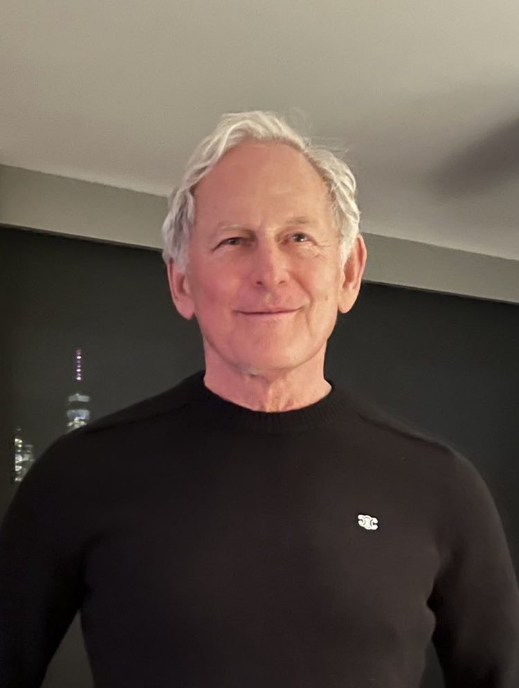 Ator Victor Garber com cabelos brancos e camiseta de manga longa preta