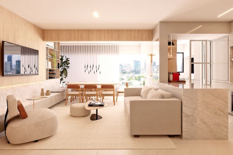 Apartamento pequeno decotado em tons claros, com sofás, tapete e puffes em bege, varanda integrada e mesa ao fundo
