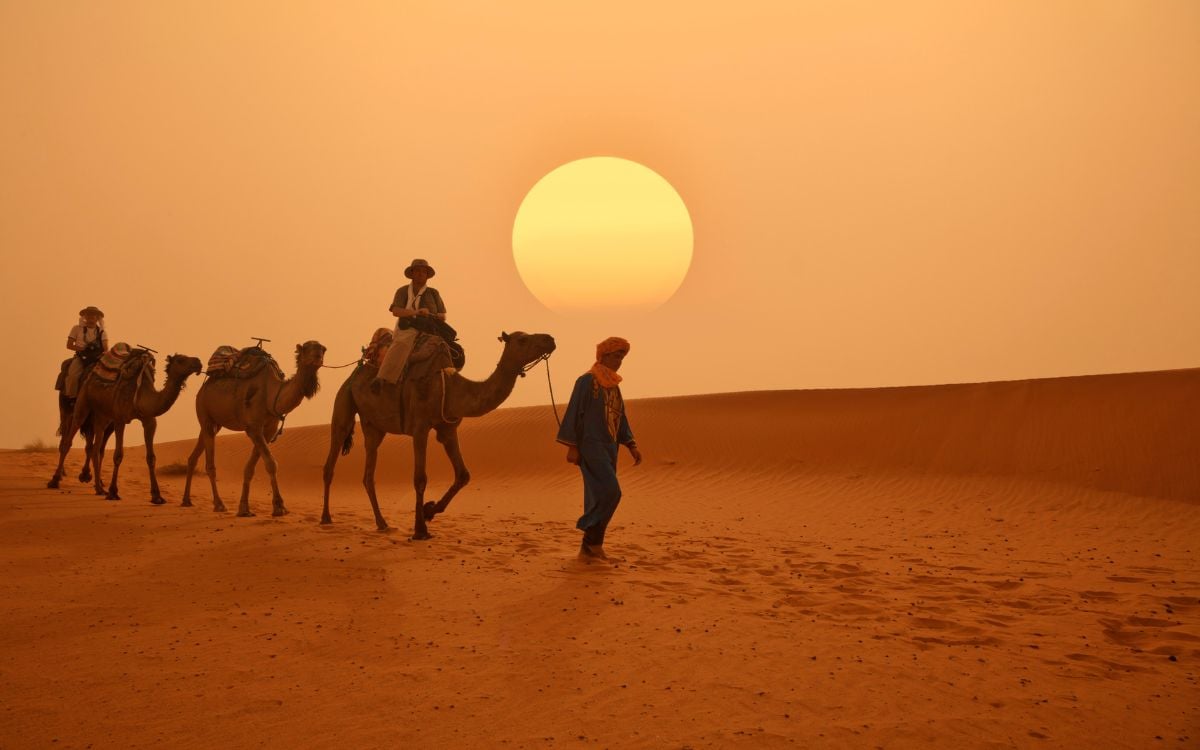 foto de pessoas andando de camelo no deserto do Saara em viagem ao Marrocos