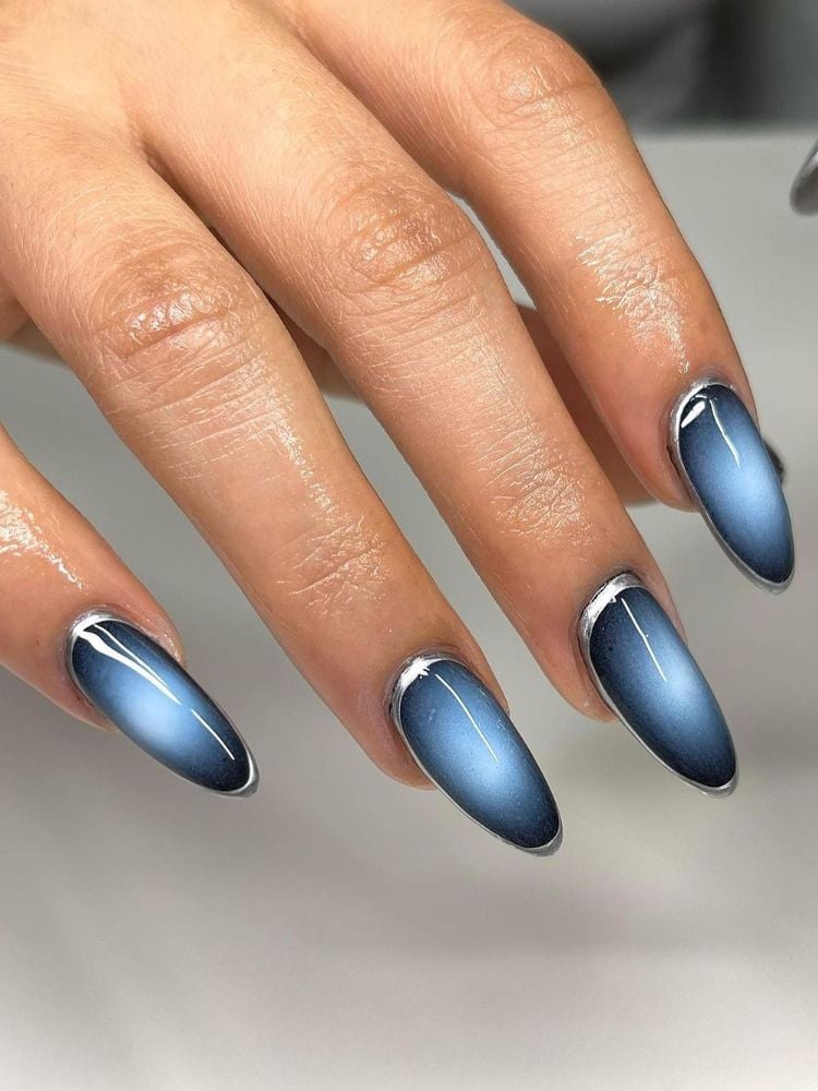 Pessoa de pele clara com uha almond estilo aura nails em azul escuro e claro 