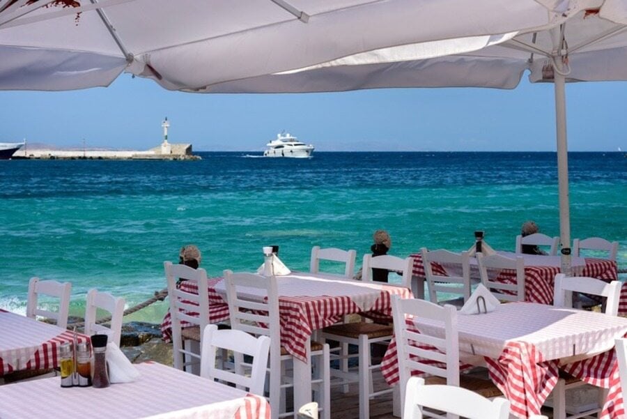 restaurante em frente ao oceano com cadeiras brancas e toalhas coloridas