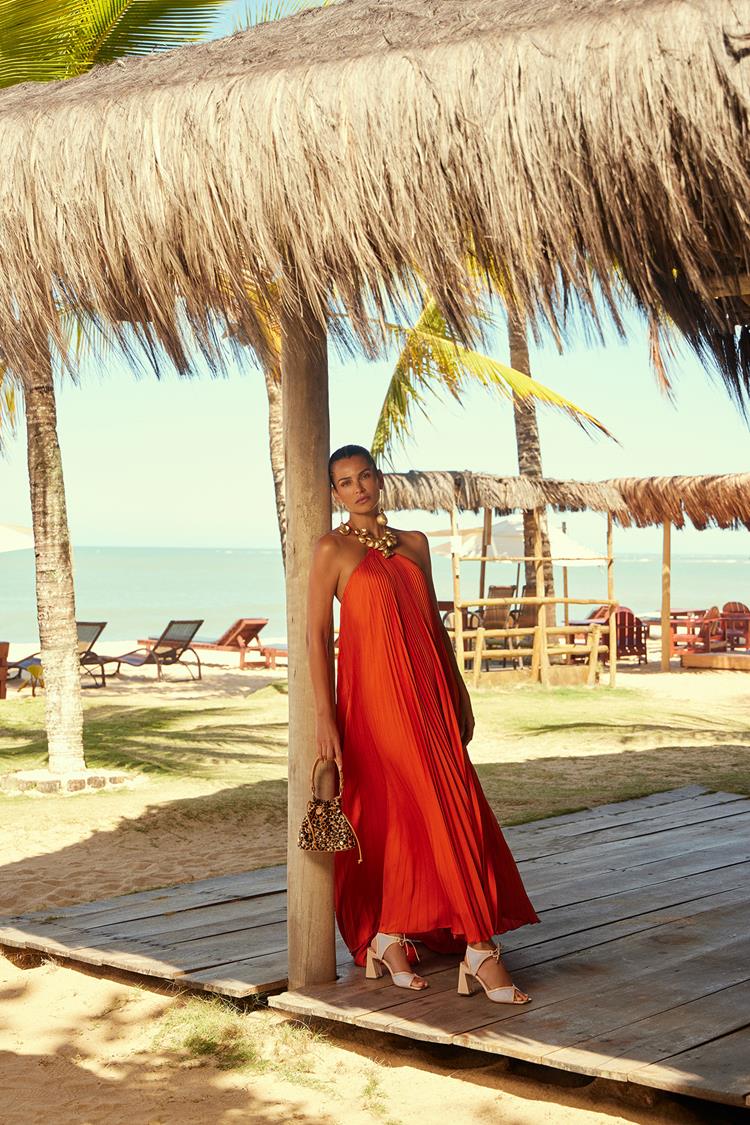 mulher na praia com vestido longo laranja