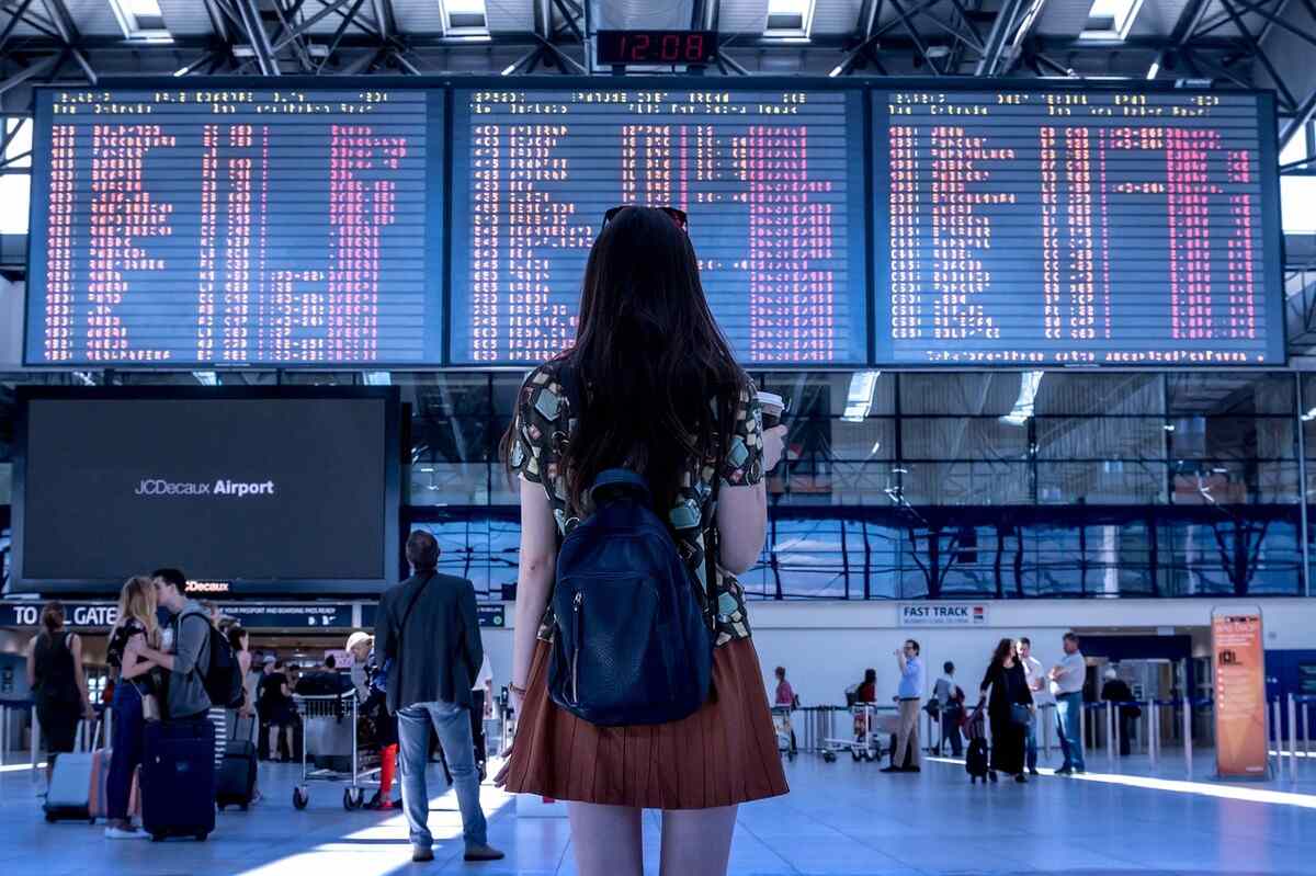 mulher olhando para um painel com horários de voo em um aeroporto