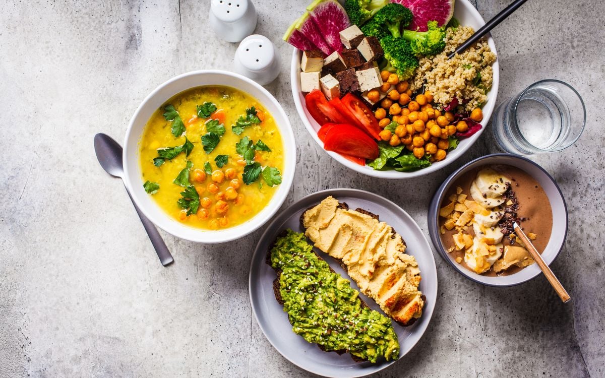 foto de pratos de uma dieta begana saudável vista de cima: bowl, sopa de grão-de-bico, pão com avocado e com homus e mingau de aveia