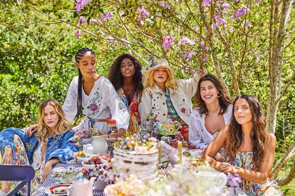 coleção garden party do cantão, seis mulheres sentadas em uma mesa ao ar livre, inspirado no chá de alice no país das maravilhas