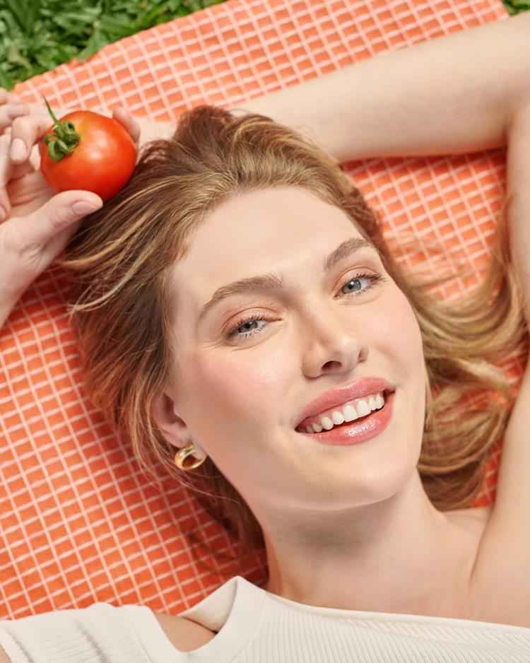 mulher deitada em gramado com maquiagem tomato girl