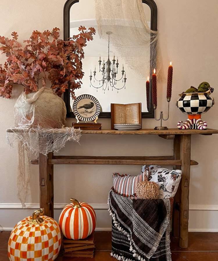 Cantinho de casa decorado no tema Halloween: abóboras, almofadas, tecidos, folhas, livros, velas