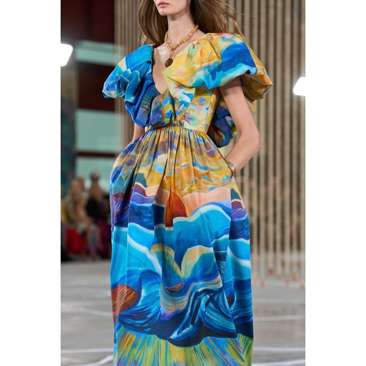 modelo com vestido longo de manga bufante, estampa em tons de azul, amarela e verde