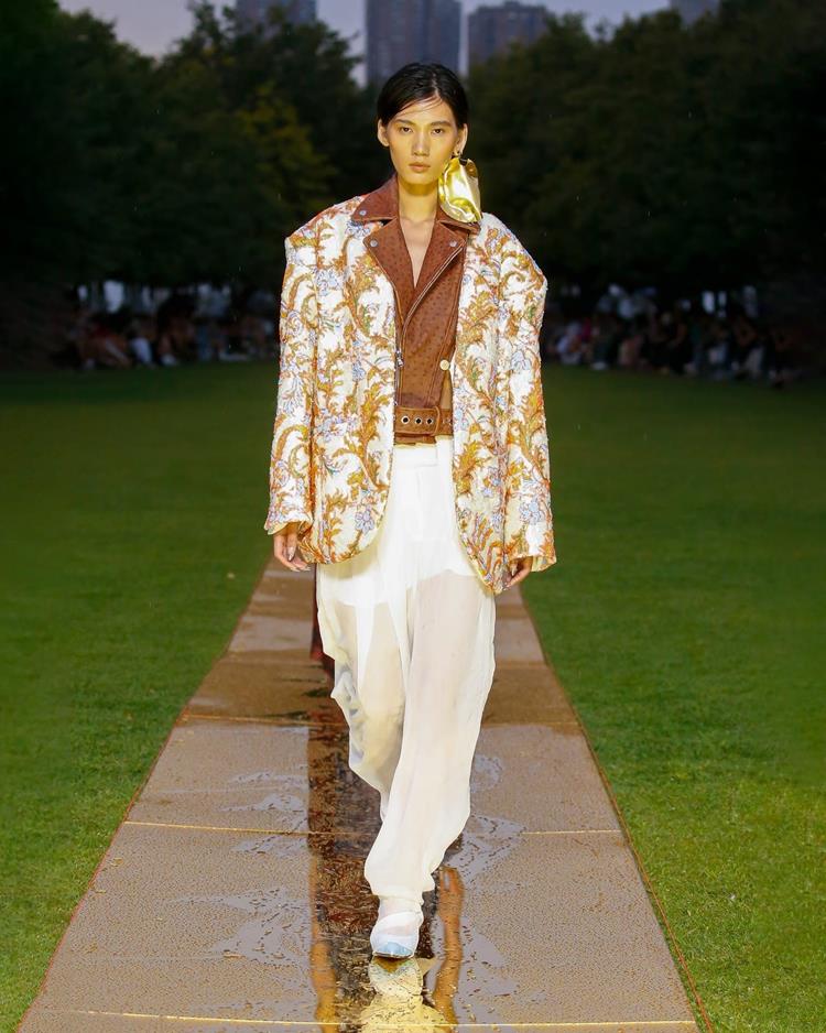 modelo com calça rosa, jaqueta de couro marrom por dentro de blazer branco estampado
