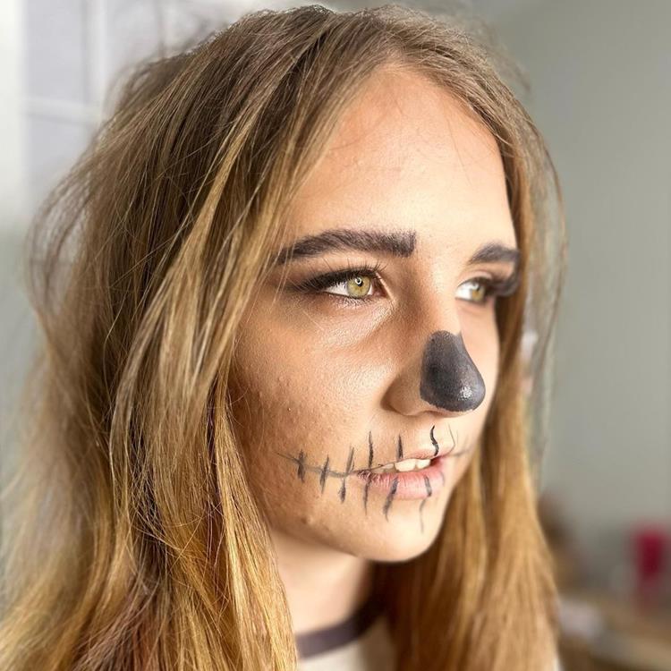 mulher com maquiagem básica de halloween imitando caveira