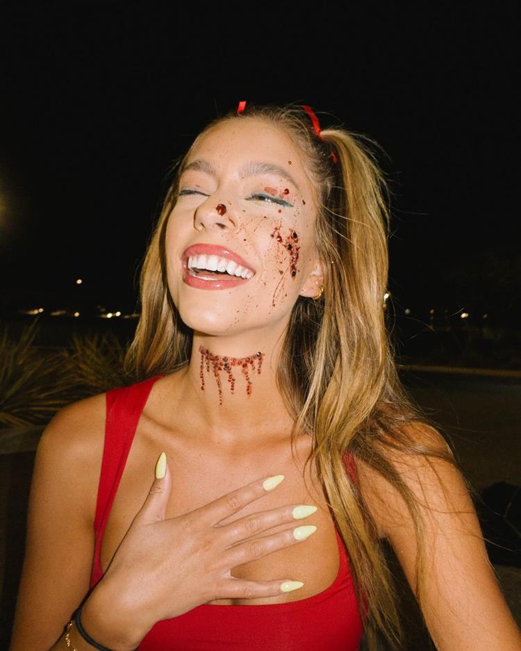 mulher com maquiagem de halloween simples, sangue falso pelo rosto e corte pequeno com glitter no pescoço