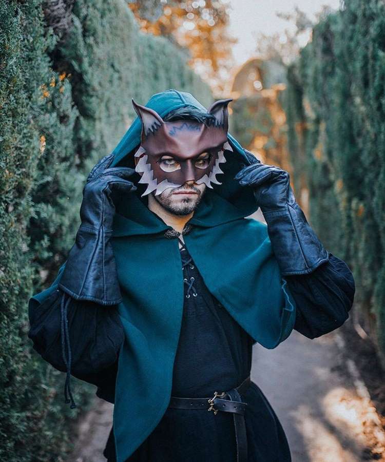 Homem com capa verde, máscara de lobo, fantasia de Halloween